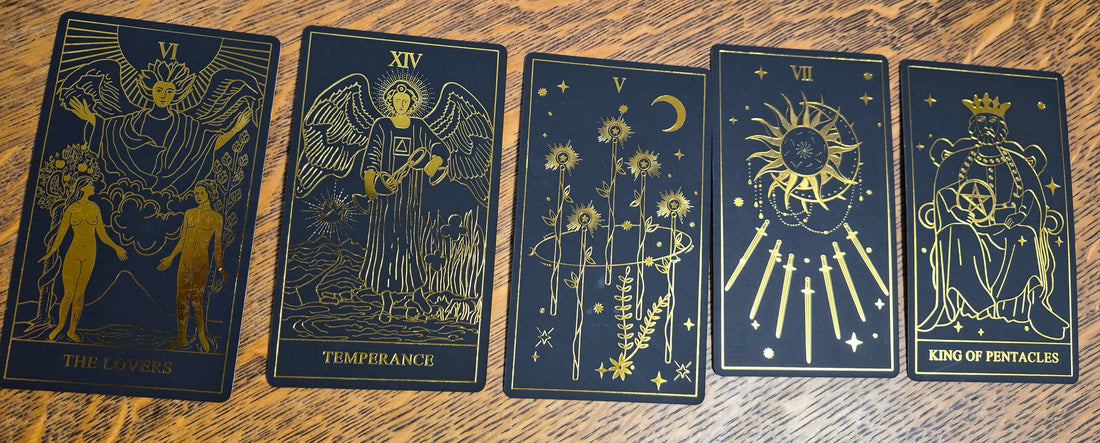 Five-card tarot spread showing The Lovers, Temperance, Five of Wands, Seven of Swords, and King of Pentacles on a wooden surface.