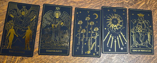 Five-card tarot spread showing The Lovers, Temperance, Five of Wands, Seven of Swords, and King of Pentacles on a wooden surface.