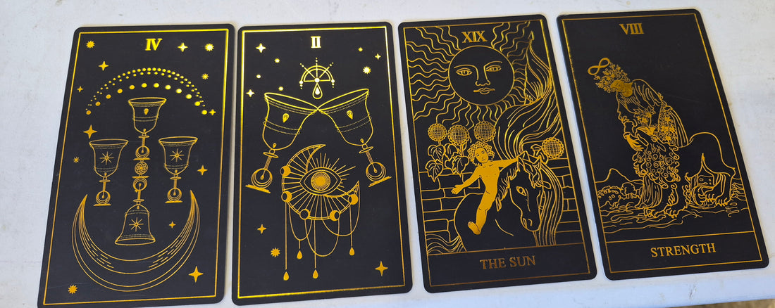 Four upright black-and-gold tarot cards: Four of Cups, Two of Cups, The Sun, and Strength.