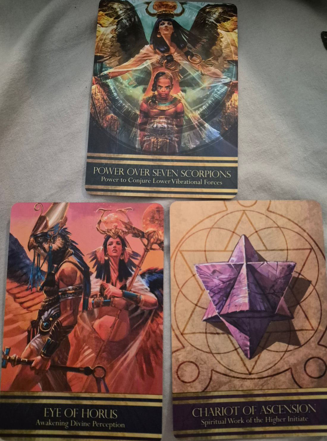Three oracle cards: Power Over Seven Scorpions above Eye of Horus and Chariot of Ascension.