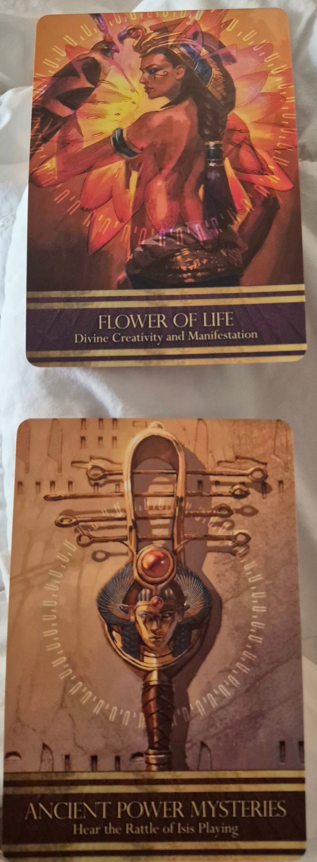 Two oracle cards: Flower of Life, Divine Creativity and Manifestation, and Ancient Power Mysteries, Hear the Rattle of Isis Playing.