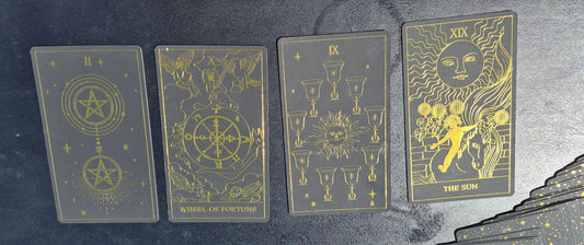 Four tarot cards laid out on a dark surface: Two of Pentacles, Wheel of Fortune, Nine of Cups, and The Sun