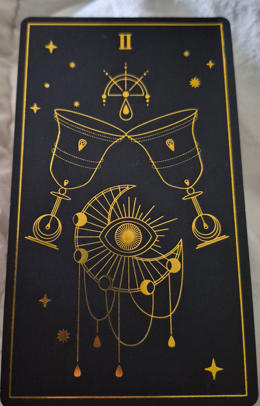 Two of Cups tarot card — black and gold design with moon phases and chalices