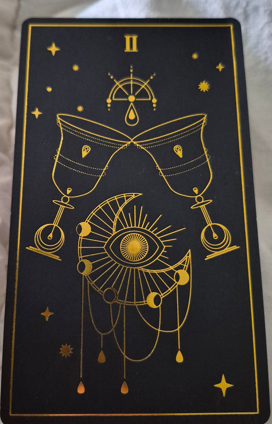 Two of Cups tarot card — black and gold design with moon phases and chalices