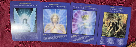 Four Archangel Michael oracle cards spread on a red velvet cloth