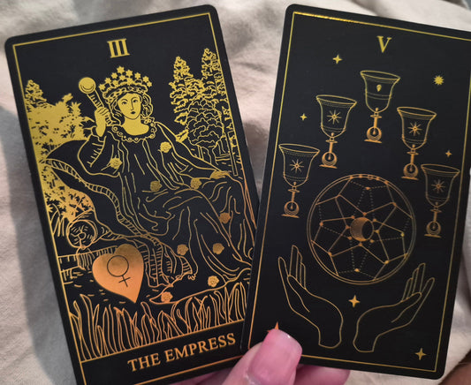Daily collective tarot reading cards – The Empress and Five of Cups from a black and gold tarot deck