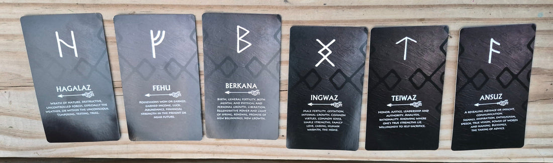 Six Elder Futhark rune cards laid out for a daily collective reading: Hagalaz, Fehu, Berkana, Ingwaz, Teiwaz, and Ansuz